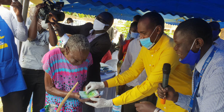 Minister Tumwebaze handing over Shs150,000 to a SAGE beneficiary in Lira town