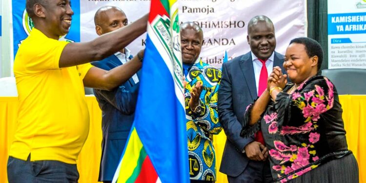 Prime Minister Robinah Nabbanja (Right) handing over EAC Flag to Rwandan Representative at the Conclusion of World Kiswahili Day in Kampala