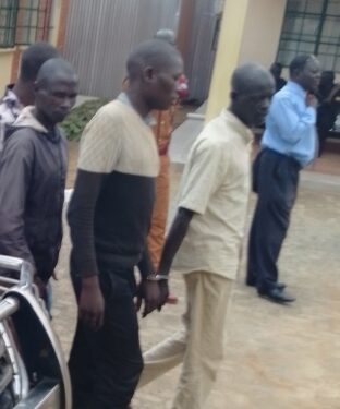 The accused wearing a black and cream sweater being escorted to Soroti grade one court where his case was mentioned today