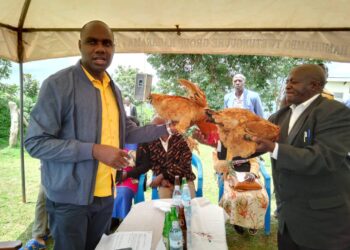 Musasizi being gifted a hen by the farmers at HamuhamboTrading Center after the meeting