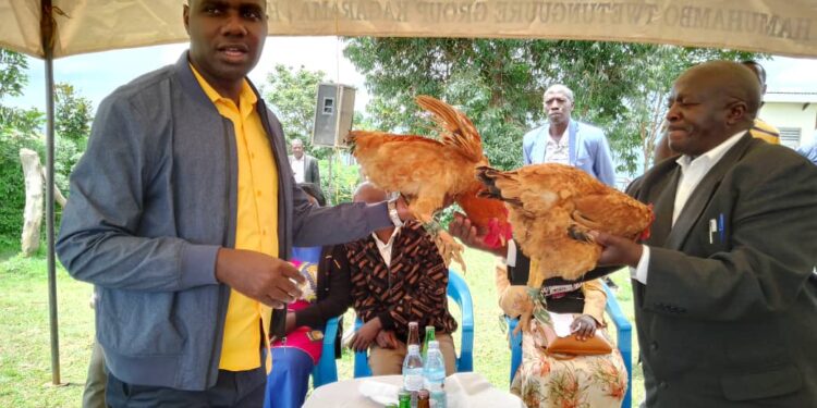 Musasizi being gifted a hen by the farmers at HamuhamboTrading Center after the meeting