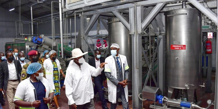 Francis Mugabe (2nd R), proprietor of Kike Tropical Fruit factory in Kakooge, Nakasongola and his team take President Museveni on a guided tour of the factory shortly after its commissioning on Thursday. PPU