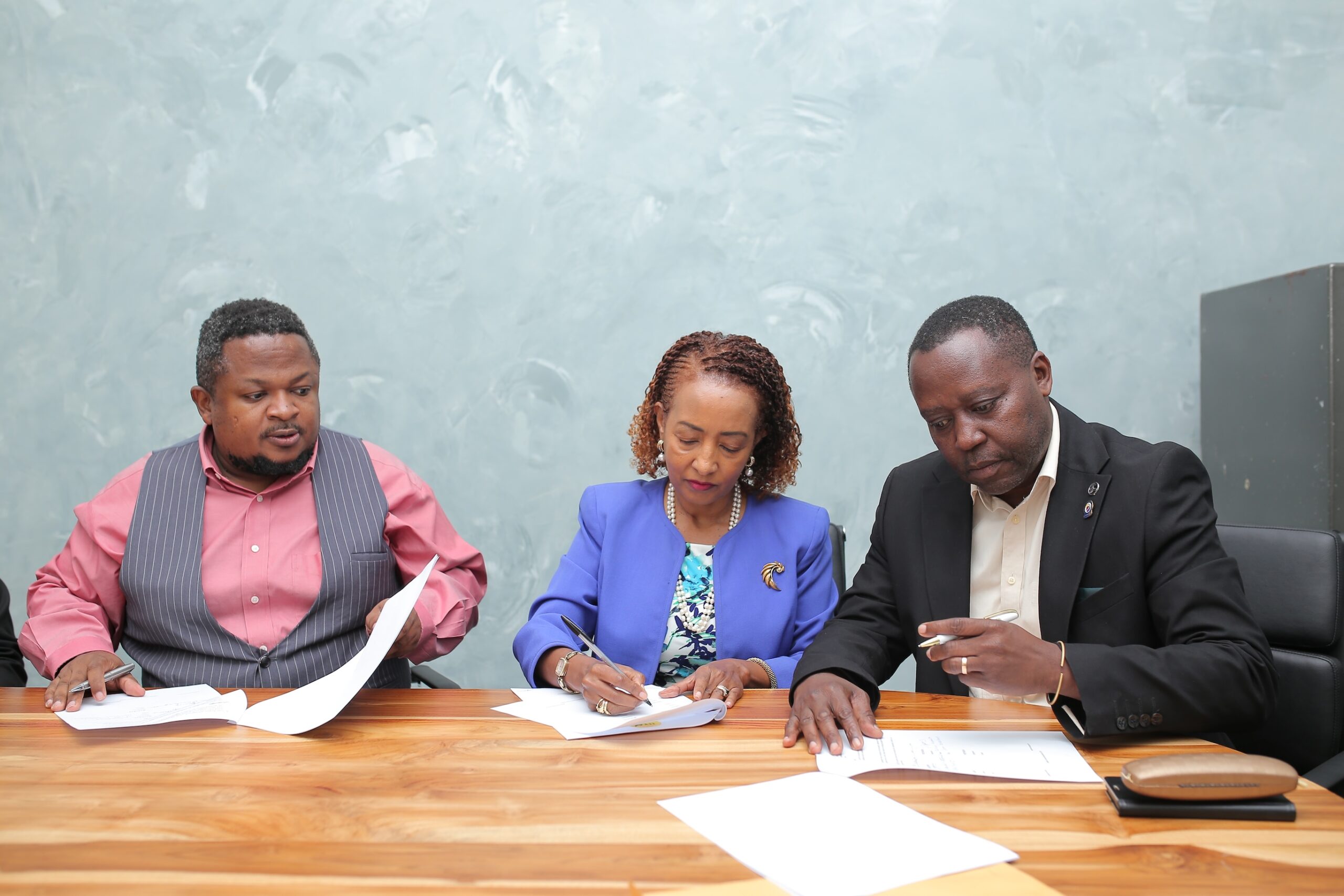 Left-Right: Muhereza Kyamutetera, Chief Executive Officer, Yewagnesh Biriggwa (Yogi), the President and Peter Mwanja, the General Secretary, sign contracts.